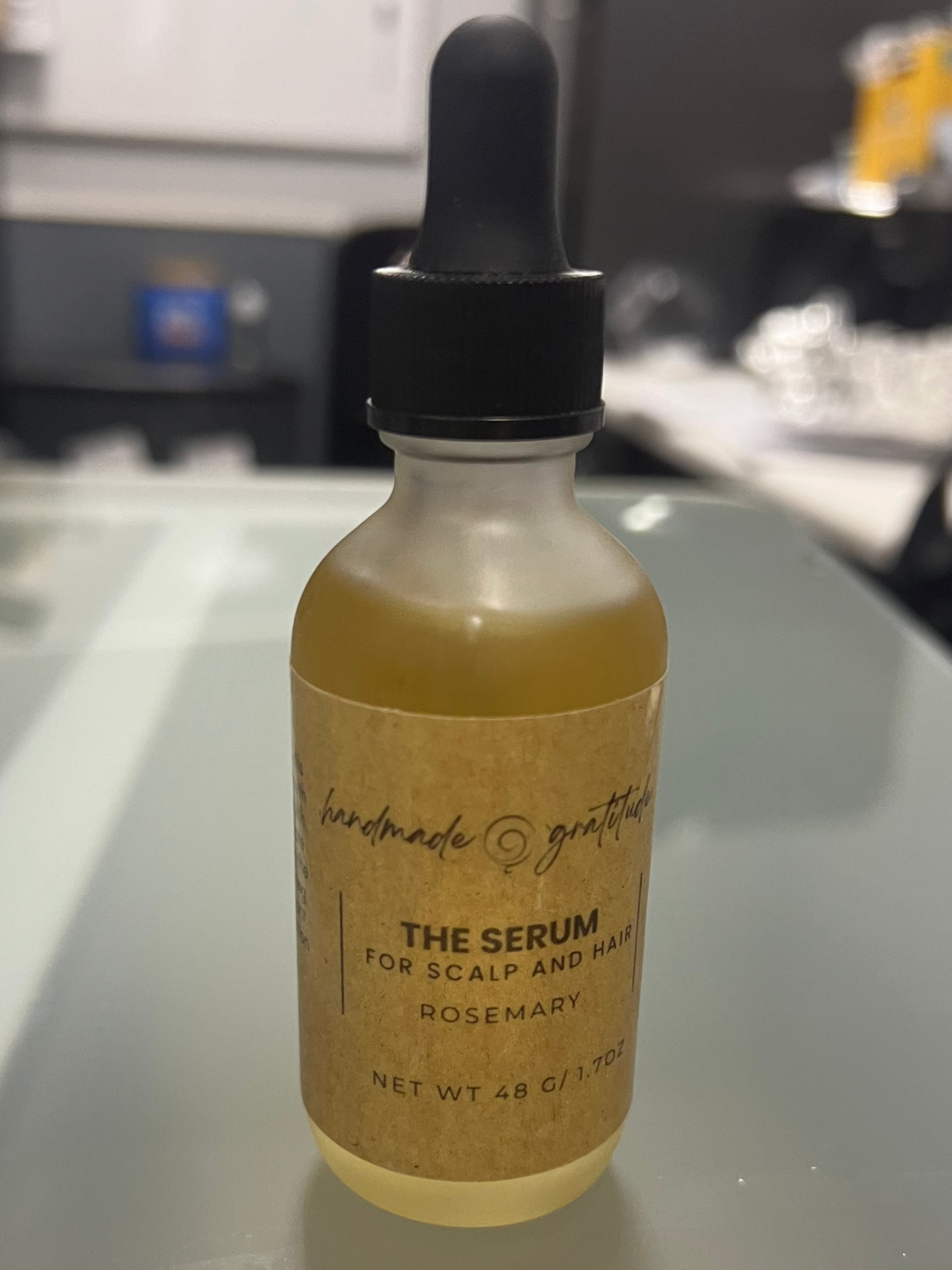 Bottle of 'The Serum' with a dropper on a reflective surface